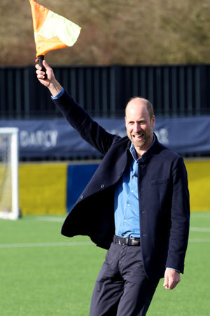 The Prince of Wales waves the linesman's flag during a mini football game at Sporting Khalsa FC in Willenhall