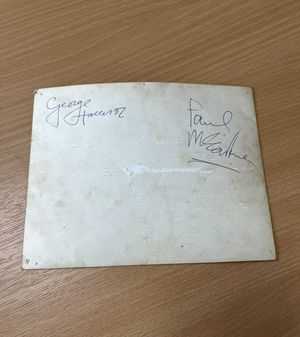 George Harrison and Paul McCartney signed their signatures on the back of the image