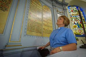 Rev Helen Morby looking at a panel inside the church inscribed with the Lord's Prayer and the 10 Commandments