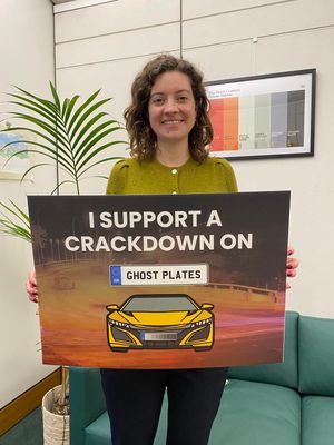 Sarah Coombes MP stands with a placard which says Crackdown on Ghost Plates