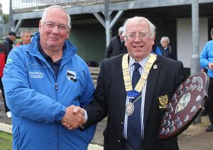 A smiling Wrockwardine Wood skipper John Clarke receives the consolation shield from county president Simon Fullard