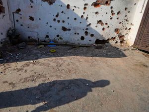 A villager walks past a wall of house riddled with shrapnels from Pakistani artillery shelling at RS Pura