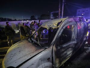 Lebanese army soldiers and rescue workers gather next to a damaged car after an Israeli strike, in the southern port city of Sidon, Lebanon
