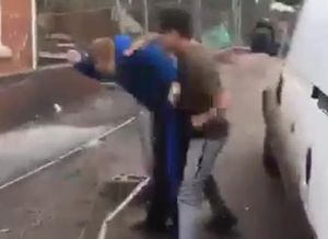 Sean is pushed up against a metal fence
