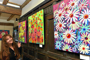Exhibition organiser Sue Miller is seen with some the the work from flower painter Ann Easthope, from Wellington