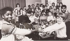 Sweetman Street Tenants Association, St Jude's Infants School, Wolverhampton. The association held a children's Christmas party. The photograph shows Maxine Grant and Carl Nash pulling a cracker, with a group of children gathered behind in December 1979.