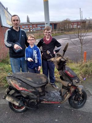 Scott Hargood, and sons Finley, nine, and McKenzie, 12, with the motor scooter they recovered from the canal