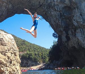 Emily Youll takes a leap into the River Ardeche beneath the ginat natural arch at Vallon Pont D’Arc