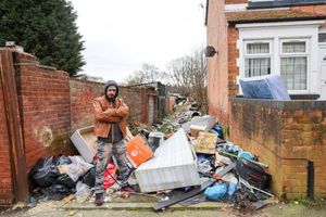 Image shows Raj Chonk standing next to fly-tipping pile at the rear of Slade Road in Stockland Green, Birmingham.