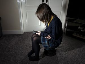 A child sits holding a mobile phone