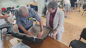 Bishop Sarah having her suitcase repaired by Peter