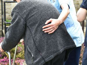 A woman helping an elderly man to walk