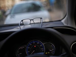 A pair of glasses resting on the dashboard of a car