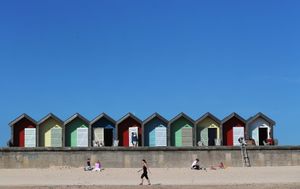People enjoy the sunshine by the beach huts on Blyth Beach in Northumberland
