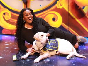 Alison Hammond on stage with a guide dog puppy. 