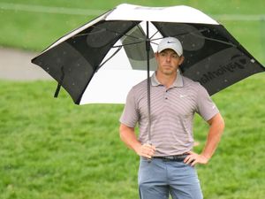 Rory McIlroy holds an umbrella