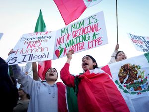 Demonstrators hold signs and shout slogans during a protest calling for immigration reform