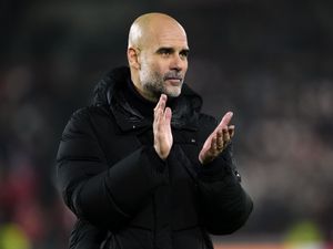 Pep Guardiola, dressed in black, applauds after a game