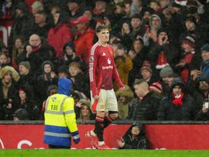 Alejandro Garnacho pulls a face as he walks towards the tunnel in the rain at Old Trafford