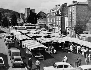 May 16, 1986 - the new look for Ludlow's open air market on the town hall site. The story starts: 'The threat of legal action by Ludlow market traders over the move to an open air site has receded now that the stalls have been set up in their new home. South Shropshire District Council went into private session to consider the market saga after receiving a letter from the national Market Traders' Federation warning of possible litigation.' The site was where Ludlow Town Hall stood, but was demolished only a few months beforehand