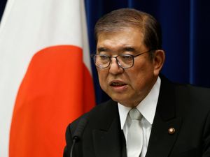 Prime Minister Shigeru Ishiba, with a Japanese flag behind him, speaks during a news conference