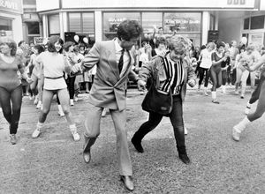 Dancer and television personality Lionel Blair leads locals in some aerobic dancing on Saturday, May 5, 1984. The caption reads: 'Twelve year old Tracey-Jane Pooler (striped top) of Horton, near Wellington, joins TV personality Lionel Blair in some open air aerobic dancing at the official opening of the Bradford and Bingley Building Society Telford and Country Property Centre in Wellington today.'