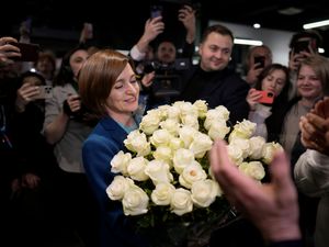 Maia Sandu smiles while holding a bouquet of flowers