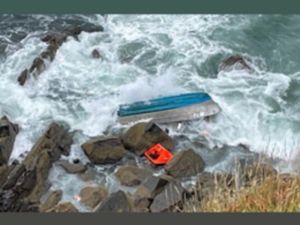 Aerial view of the upturned Lexi Rose vessel on rocks, with waves crashing over it