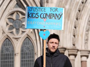 Man standing outside the High Court holding a sign which reads 'Justice for Kids Company'