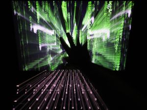 A zoom burst photo of a user touching the screen of a laptop displaying a ‘Matrix’-style screensaver