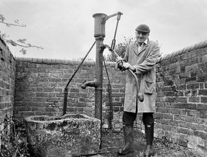 Mr Bill Powis and the village pump at Berrington. The accompanying story was of 69-year-old Mr Powis, of Grove Farm, Berrington, recalling how when he was a lad the pump was a vital factor in everyone's life, and the focal point at which the 140 children at the village school used to gather to eat their lunch. Everyone relied on it for their water, making it a meeting place, but with the coming of piped water it was allowed to become derelict, 'until the parish council decided it ought at the very least to look like a pump and not to disappear altogether. Atcham Rural District Council had handed over the pump to the parish and Mr Powis had put it into something like working order, although it did not pump water. July 1973.