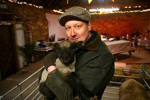 Farm Co-Owner John Franklin-Hackett holds a lamb in The Old Barn at the farm.