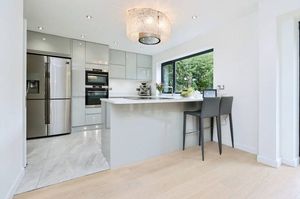 A sleek high-gloss kitchen with breakfast bar and bi-fold doors opening out to the garden