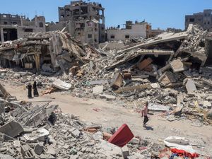 Palestinians walk amongst rubble
