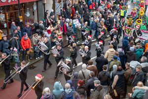 A brass band marches through playing festive tunes