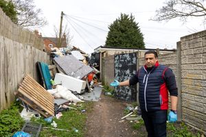 Malik Abbas standing next to fly-tipping pile at the rear of Slade Road in Stockland Green, Birmingham.