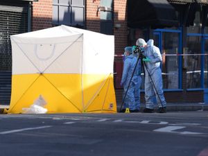 Forensic officers next to a yellow and white forensics tent