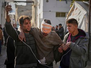 An injured man is helped by two others