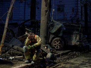 A rescue worker rests near a university building destroyed by a Russian missile strike in Ukraine