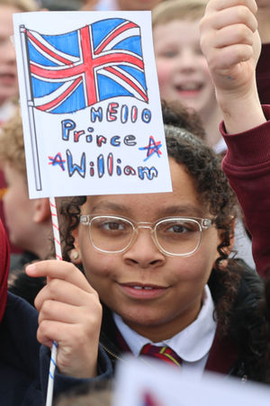 A schoolchild from Fibbersley Park Primary Academy waves a Union flag with "Hello Prince William" written on it