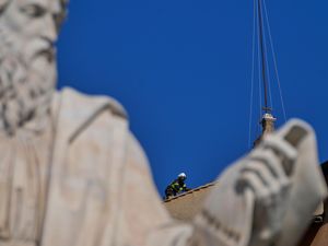 Firefighters install the chimney, with a statue in the foreground