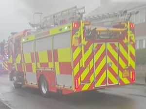 A West Midlands Fire Service vehicle shrouded in smoke from the fire. 