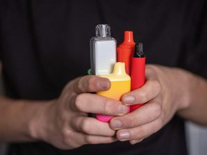 Teenage boy's hands holding unbranded disposable vapes