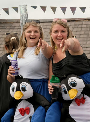 Two members of a float full of penguins point to spectators in the crowds on the parade. Image by Andy Compton