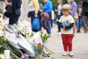A young child looks at flowers outside Buckingham Palace. Photo: Kirsty O'Connor/PA Wire