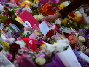 A person places a card at a memorial for victims after a vehicle drove into a crowd during a Filipino heritage festival in Vancouver, British Columbia