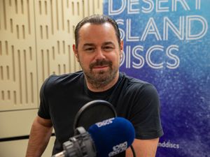 Danny Dyer sitting in front of a microphone in a radio studio in front of a Desert Island Discs banner