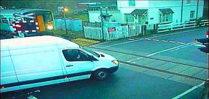 The white van driver moves onto the crossing even though a train is approaching