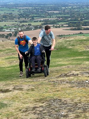 Headteacher Tom Lowrie-Herz (left) and dad Andy O'Brien help Myles up the hill. Picture: Pontesbury Primary School