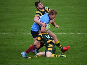 Two rugby players in yellow and green tackling a player in blue